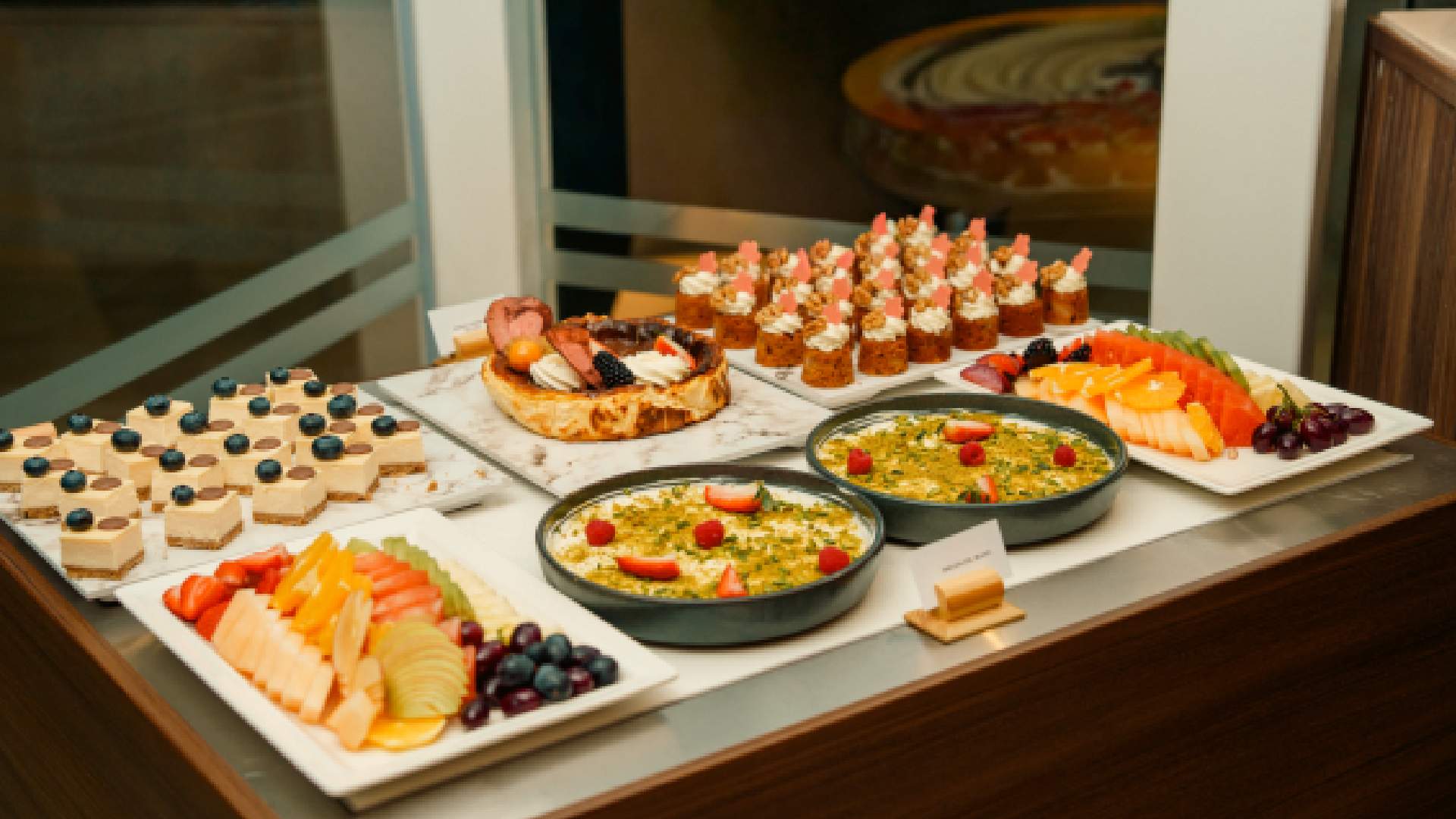 Iftar dessert and fruit buffet display at MÖVENPICK DOWNTOWN featuring assorted cakes, mini pastries, fresh fruit platters, and traditional Ramadan desserts arranged on a serving counter.