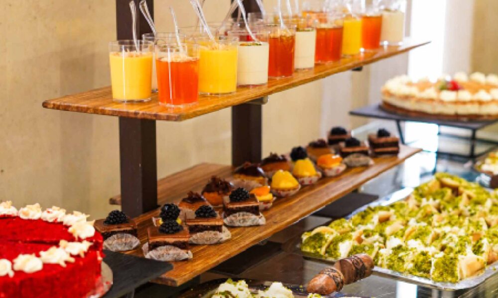 Dessert and beverage station at Bab El Bahr featuring layered cakes, mini pastries, Arabic sweets and assorted juices displayed on a buffet stand
