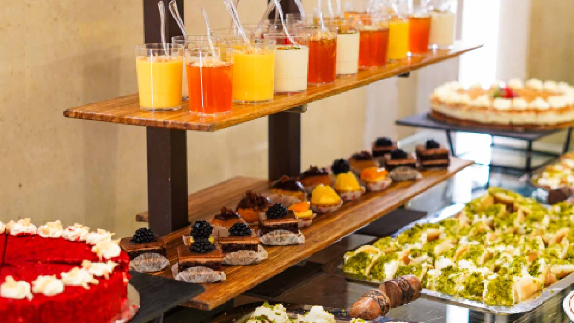 Dessert and beverage station at Bab El Bahr featuring layered cakes, mini pastries, Arabic sweets and assorted juices displayed on a buffet stand
