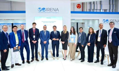 HOLCIM UAE delegation standing with industry stakeholders at the IRENA pavilion during an official alliance announcement event, with IRENA branding displayed in the background.