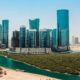 Aerial view of Al Reem Island showing modern high-rise towers along a waterfront canal, sandy shoreline, and landscaped mangrove area in Abu Dhabi by OBJECT 1.