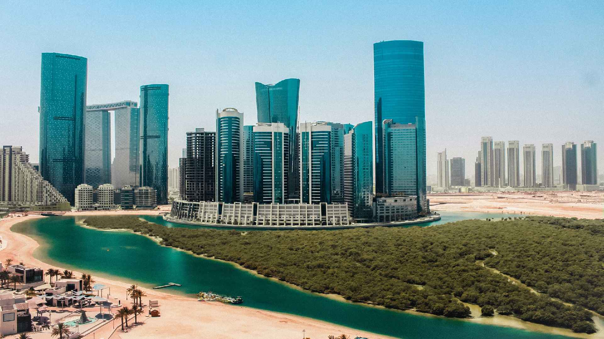 Aerial view of Al Reem Island showing modern high-rise towers along a waterfront canal, sandy shoreline, and landscaped mangrove area in Abu Dhabi by OBJECT 1.