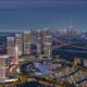 Aerial night view of Sobha Realty master-planned waterfront community featuring illuminated high-rise towers, residential villas, landscaped roads, and Dubai skyline in the background