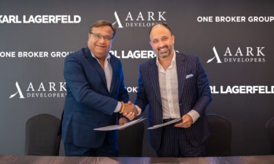 Signing ceremony between AARK DEVELOPERS and One Broker Group for Karl Lagerfeld Beach Residences, with representatives shaking hands and holding signed documents in front of branded backdrop.