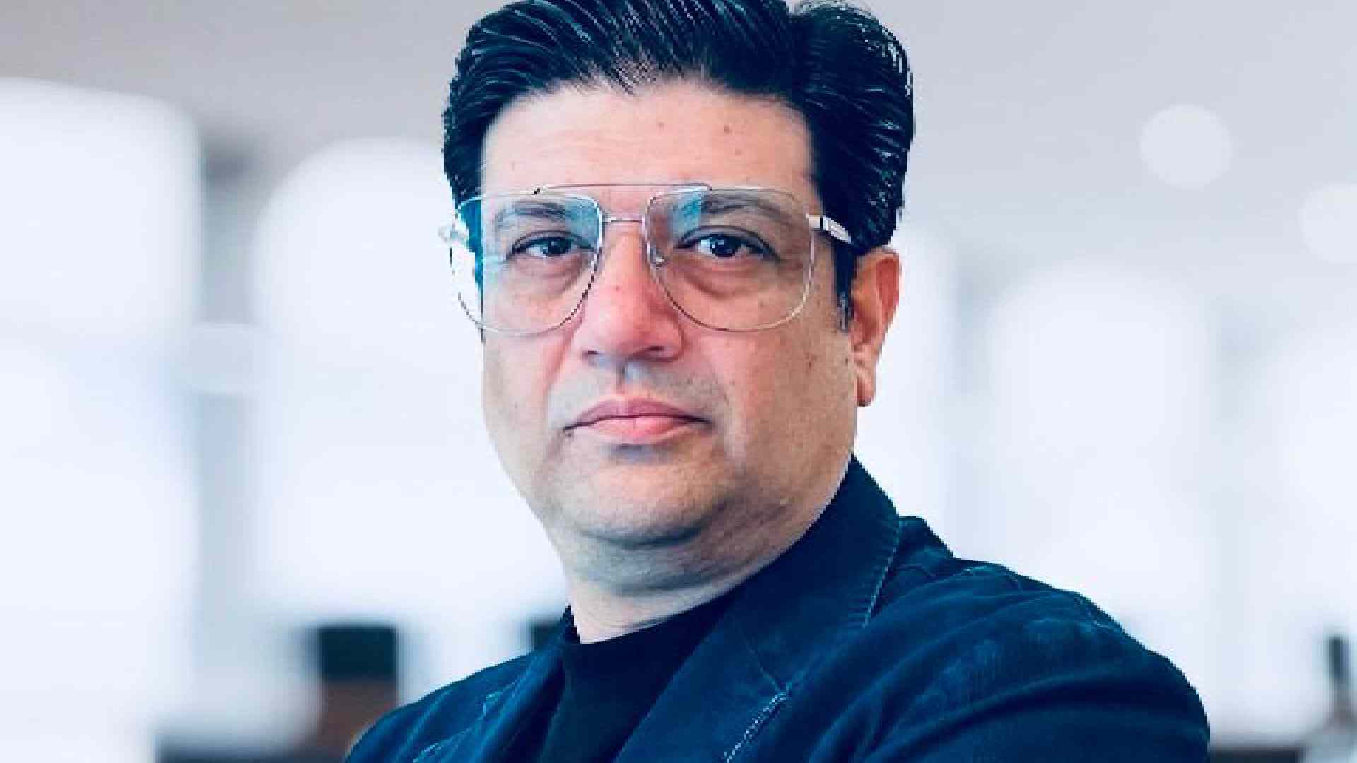 Professional portrait of a Gllit Technologies team member standing with arms crossed in a modern office setting