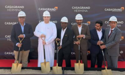 CASAGRAND HERMINA ground breaking ceremony with officials wearing safety helmets holding ceremonial shovels on a red carpet in front of CASAGRAND HERMINA branded backdrop