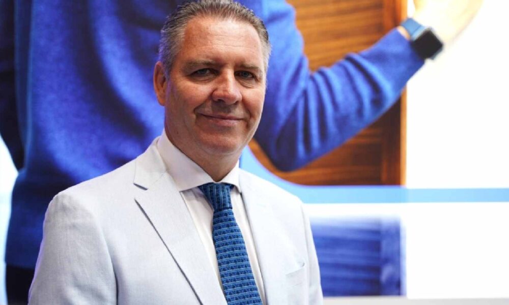 HID executive in a white suit and blue tie standing in front of a digital screen, presenting identity and access control solutions at an industry event.