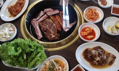 Grilled meat cooking on a tabletop barbecue, surrounded by assorted side dishes and garnishes at AL RAHA BEACH RESORT & SPA.
