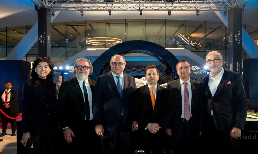 Richmind executives and partners posing at the Oystra Phase 2 launch event at Ain Dubai, standing in front of the architectural Oystra display with branded lighting and red carpet stanchions.