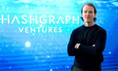 A person standing with arms crossed in front of a digital blue gradient background featuring the Hashgraph Ventures logo.