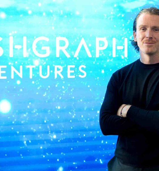 A person standing with arms crossed in front of a digital blue gradient background featuring the Hashgraph Ventures logo.