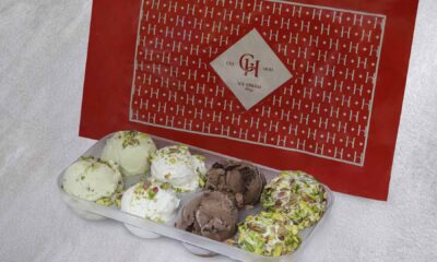 AL HALLAB ice cream sharing box displaying scoops of ashta, chocolate and mixed flavours topped with pistachios, placed in front of branded AL HALLAB ice cream packaging.