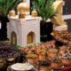 Ramadan Iftar dessert display at PURANI DILLI featuring dates, dried fruits, traditional sweets, brass bowls, crescent moon décor, palm plants and mosque-inspired centrepiece.