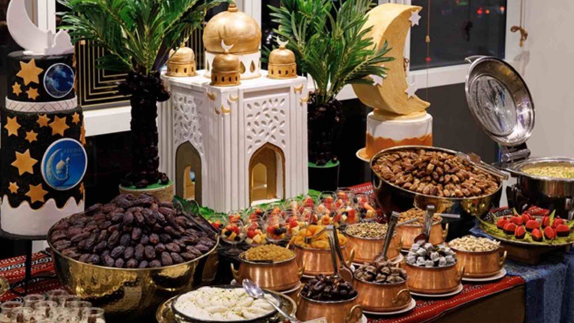 Ramadan Iftar dessert display at PURANI DILLI featuring dates, dried fruits, traditional sweets, brass bowls, crescent moon décor, palm plants and mosque-inspired centrepiece.
