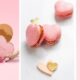 Ladurée Valentine’s macaron gift boxes displayed on a pink background, featuring heart-shaped pink macarons, branded pastel boxes, and delicate floral ribbon accents.