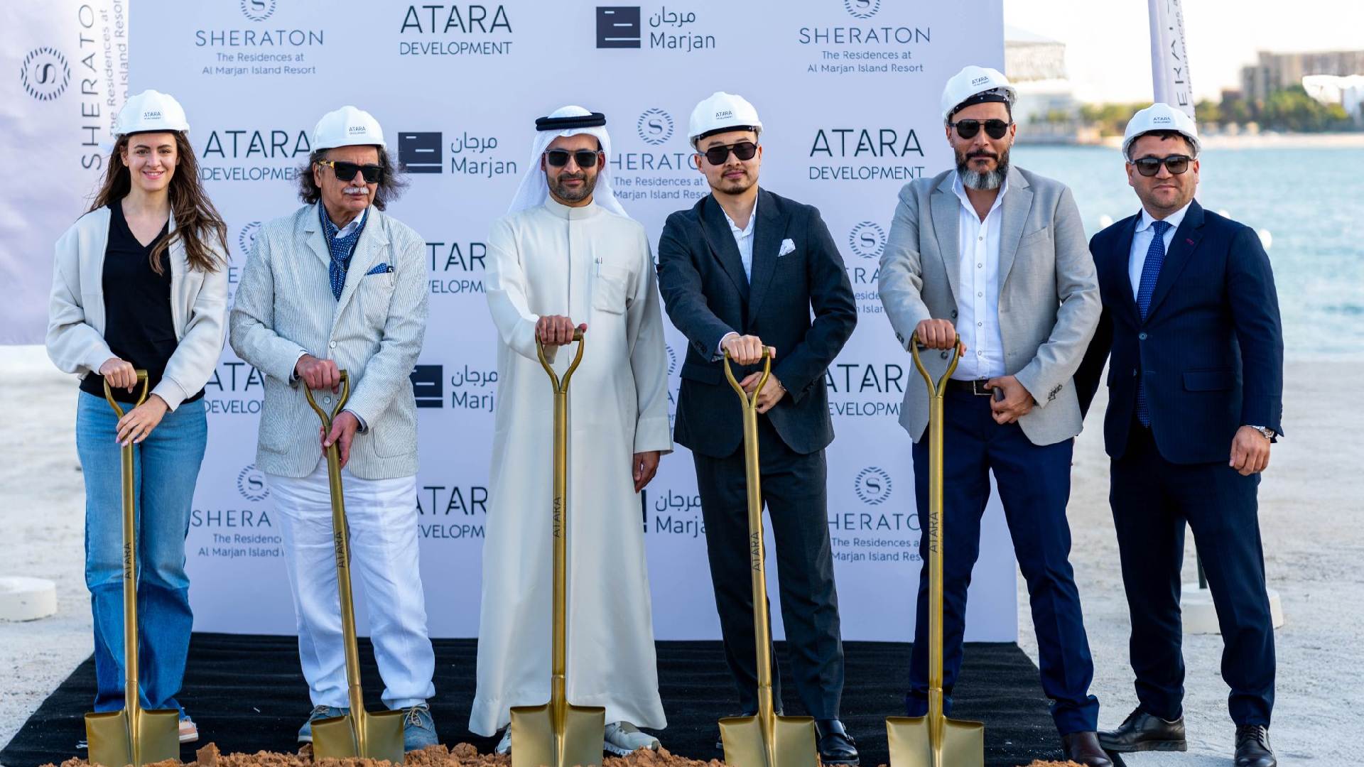 Groundbreaking ceremony for The Residences at Sheraton Al Marjan Island Resort by ATARA Development, featuring six individuals standing on a sandy site holding gold ceremonial shovels in front of a branded backdrop displaying logos of ATARA Development, Sheraton, and Marjan