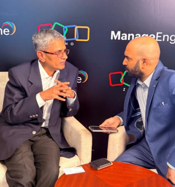 Shailesh Davey, Co-founder and CEO of Zoho, is seated in a cream-colored armchair and speaking with Srijith KN, Senior Editor at Integrator Media, who is holding a recording device. They are positioned in front of a dark backdrop featuring the ManageEngine and Zoho logos during a professional interview.