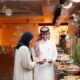 A Ramadan Iftar buffet setup at a Radisson Blu venue, featuring two guests selecting food from an elegantly arranged spread with traditional décor, warm lighting, and crescent moon ornaments overhead.