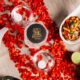 Overhead view of a romantic dining setup at Wagah Border featuring Indian dishes, kebabs, curries, candles, and red rose petals arranged on a table.
