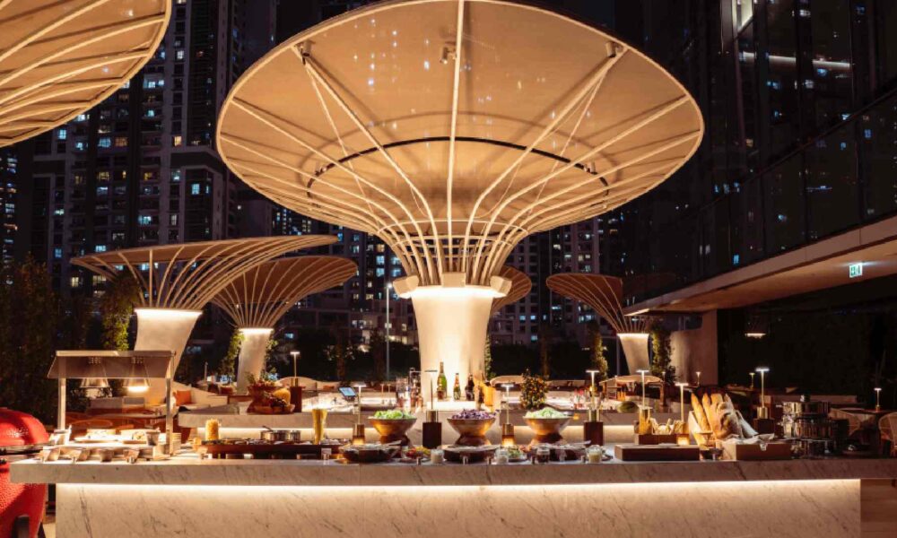 Open-air iftar buffet setup on the Pool Terrace at ME by Meliá Dubai, featuring illuminated food stations beneath sculptural canopy structures at night with the city skyline in the background.