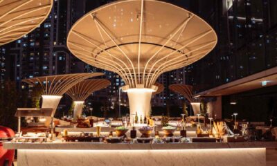 Open-air iftar buffet setup on the Pool Terrace at ME by Meliá Dubai, featuring illuminated food stations beneath sculptural canopy structures at night with the city skyline in the background.