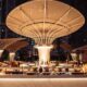 Open-air iftar buffet setup on the Pool Terrace at ME by Meliá Dubai, featuring illuminated food stations beneath sculptural canopy structures at night with the city skyline in the background.