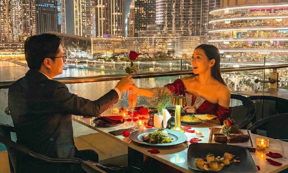 Romantic outdoor dinner at Joe’s Café Dubai with a couple dining by candlelight, exchanging a rose at a table overlooking the Burj Khalifa, Dubai Fountain, and illuminated city skyline at night.