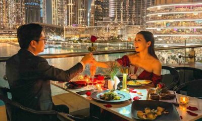 Romantic outdoor dinner at Joe’s Café Dubai with a couple dining by candlelight, exchanging a rose at a table overlooking the Burj Khalifa, Dubai Fountain, and illuminated city skyline at night.