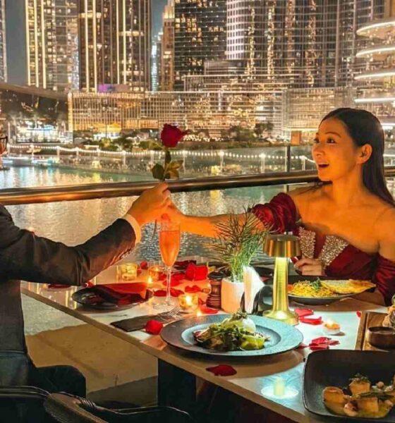 Romantic outdoor dinner at Joe’s Café Dubai with a couple dining by candlelight, exchanging a rose at a table overlooking the Burj Khalifa, Dubai Fountain, and illuminated city skyline at night.