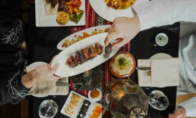 Overhead view of guests sharing a grilled meat platter with dates and Arabic dishes on a table at PARK REGIS KRIS KIN HOTEL DUBAI during Iftar.