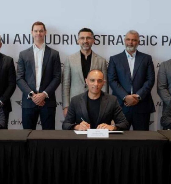 Udrive and AGMC MINI executives sign a strategic partnership agreement during an MoU ceremony, seated at a table with branded backdrop.