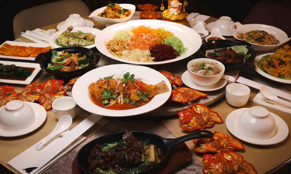 Festive Lunar New Year dining spread at TENGGARA featuring Yee Sang, seafood, soups, stir‑fried meats, white tableware, and red Chinese New Year decorations arranged for communal sharing.