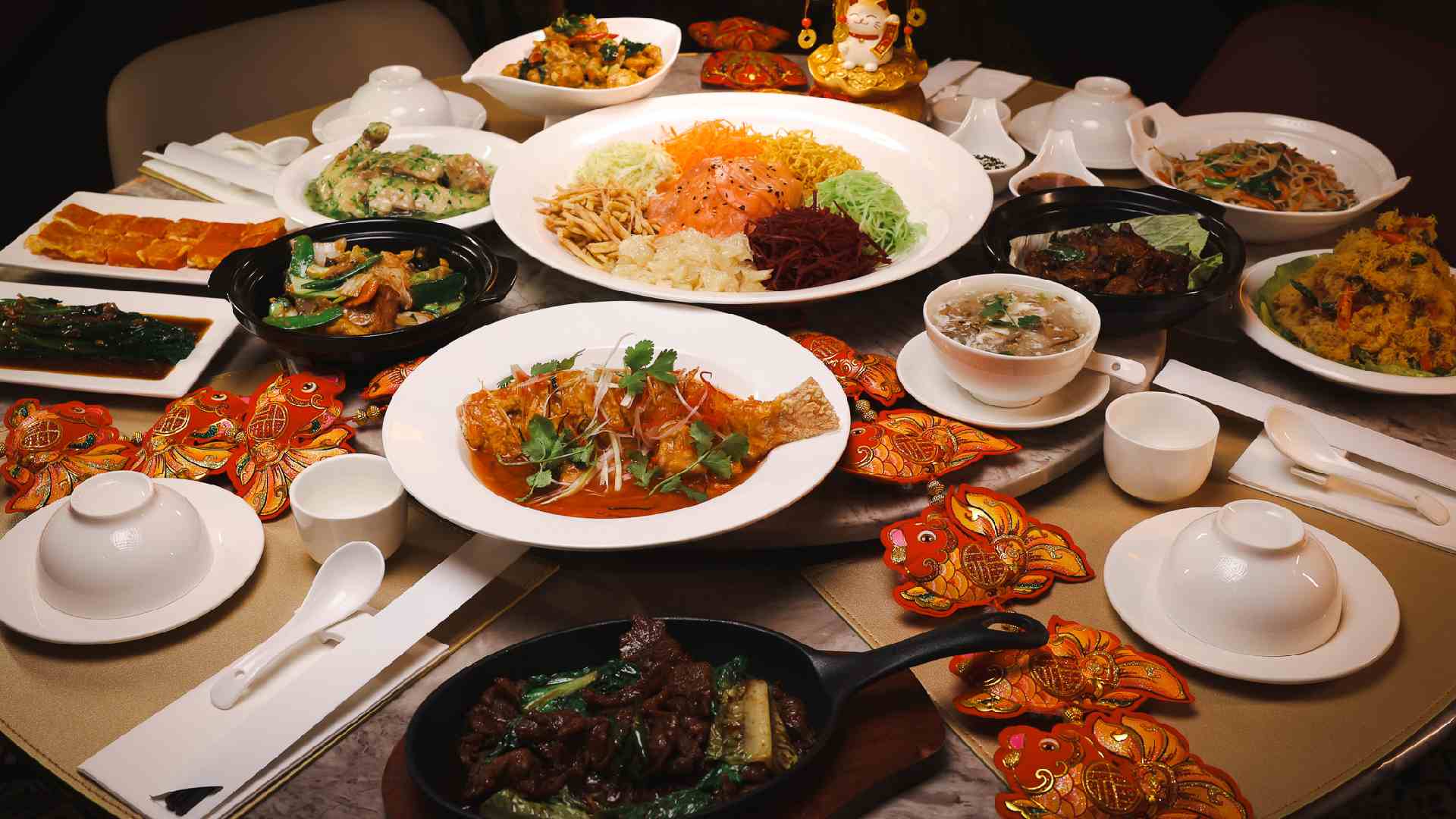 Festive Lunar New Year dining spread at TENGGARA featuring Yee Sang, seafood, soups, stir‑fried meats, white tableware, and red Chinese New Year decorations arranged for communal sharing.