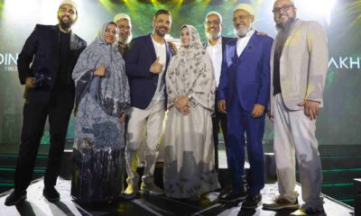A group of formally dressed individuals standing together on a stage during a Fakhruddin Properties event, with bright spotlights and branded signage illuminated in the background.