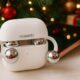 White HUAWEI FreeClip open‑ear earbuds inside an open charging case on a table, with a smartphone, Christmas tree, lights, and wrapped gift boxes in the background.