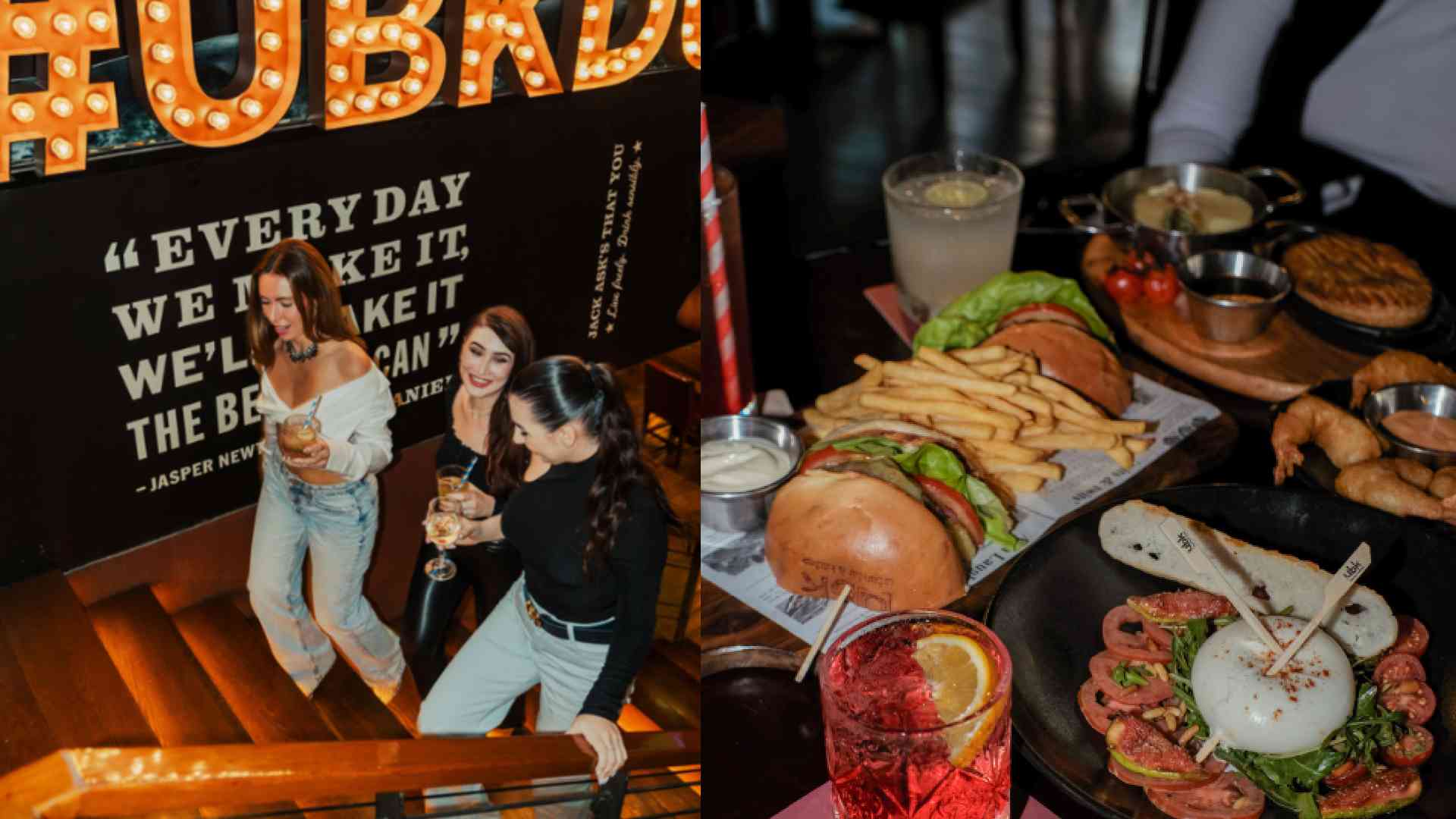 UBK venue interior showing guests socialising on a staircase beneath illuminated signage, alongside a table spread with burgers, fries, seafood dishes, and cocktails served in a lively dining atmosphere.