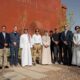 Group site visit showing senior representatives and project stakeholders standing outside the NUMAJ building in AlUla during the construction commencement milestone.