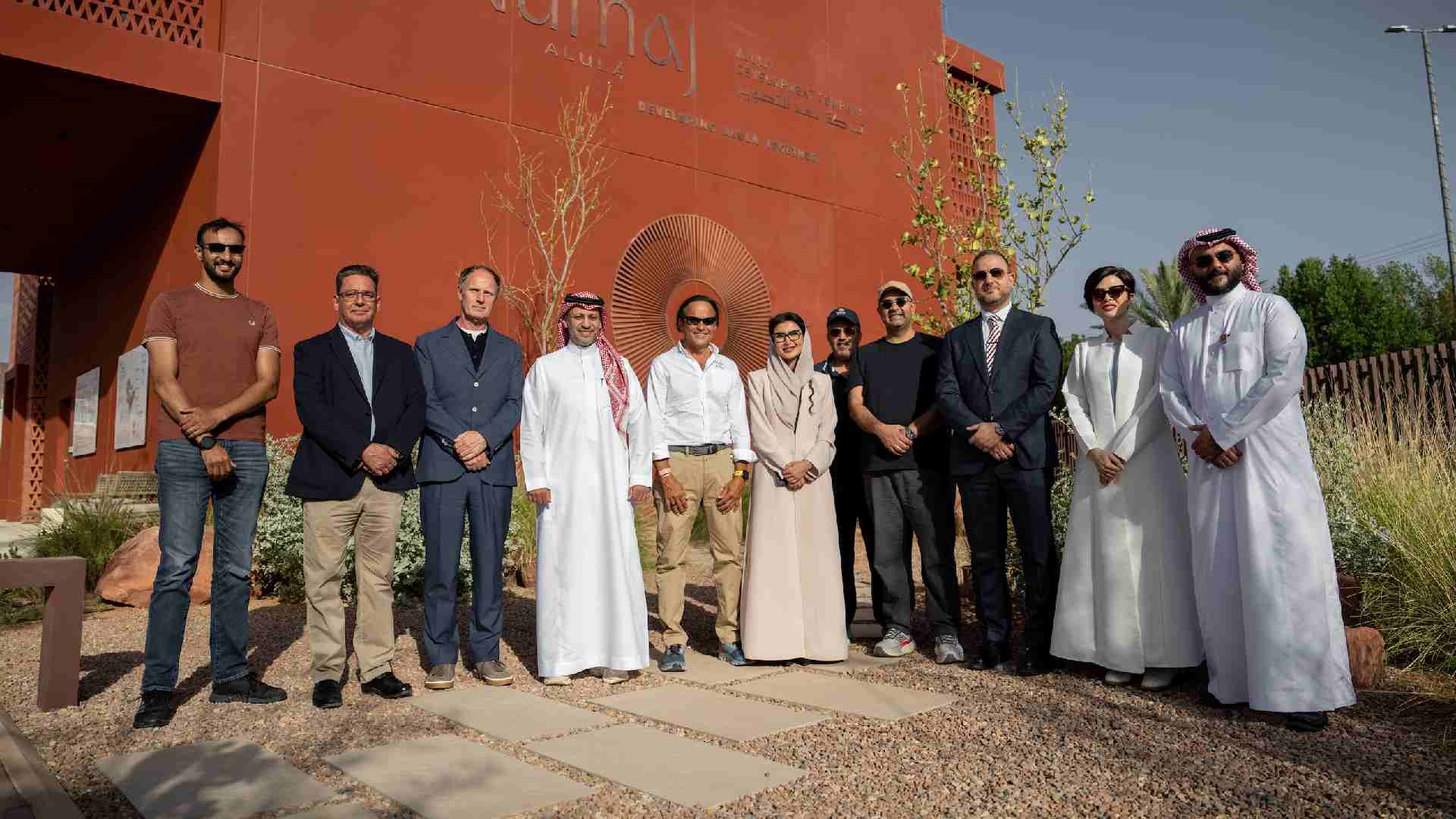 Group site visit showing senior representatives and project stakeholders standing outside the NUMAJ building in AlUla during the construction commencement milestone.
