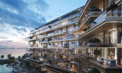 Architectural rendering of an AVENEW Development waterfront residential building at Dubai Islands, featuring multi‑level stepped balconies, floor‑to‑ceiling glass façades, landscaped terraces, and sea views at sunset.