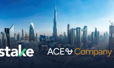 Dubai skyline with Burj Khalifa centered, featuring Stake x ACE & Company partnership branding over city skyscrapers and highways.
