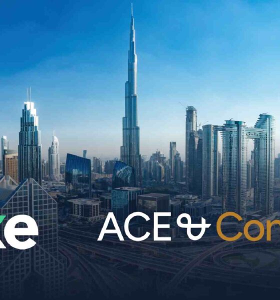 Dubai skyline with Burj Khalifa centered, featuring Stake x ACE & Company partnership branding over city skyscrapers and highways.